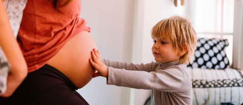 Portrait of a pregnant woman with a child hugging