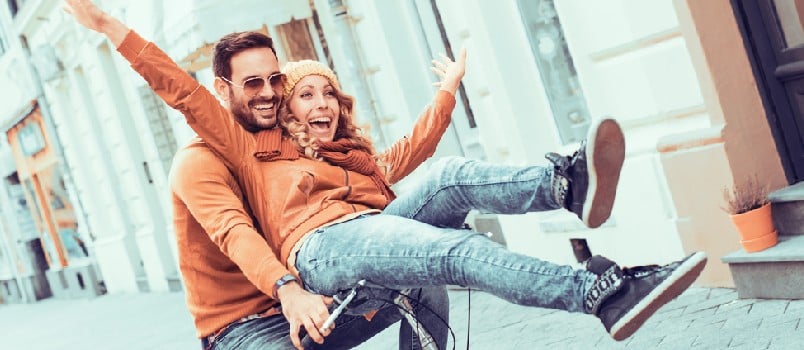 Young couple having fun in the city.Happy young couple going for a bike ride on a autumn day in the city.