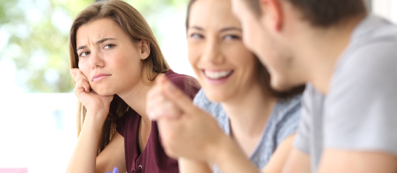 Couple in love and a jealous classmate watching them in a classroom