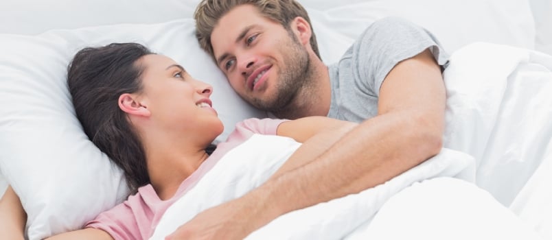Couple Embracing and Looking at Each Other While They Are Lying in Bed