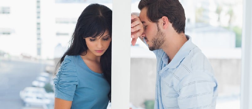 Divided couple are separated by white wall but holding hands