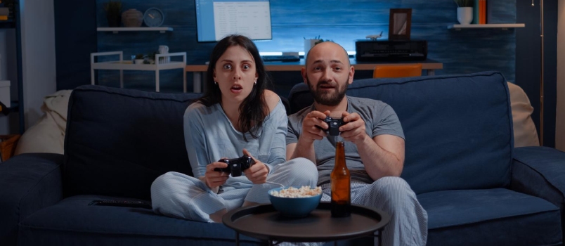 Determinated excited couple winning video games, hugged each other sitting on sofa playing