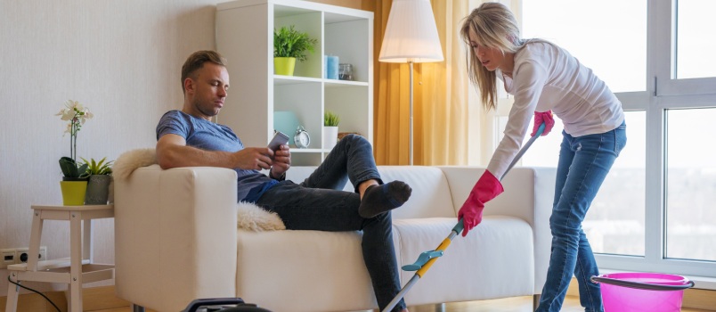 Women Cleaning the House While Man is Relaxing on the Couch