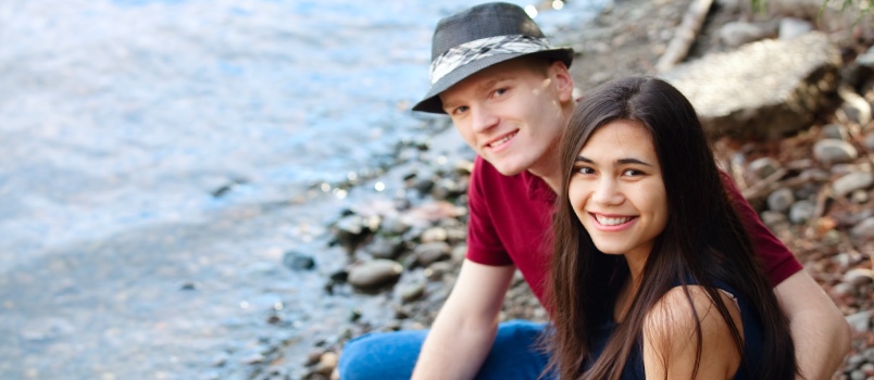 Beautiful Young Interracial Couple Sitting Together by Lake