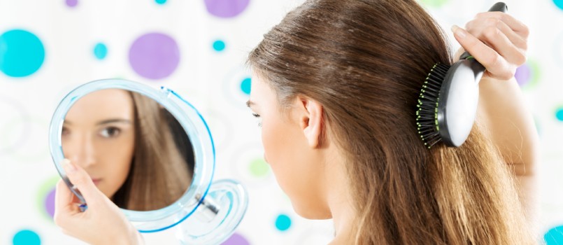 Girl looking in mirror while combing her hair