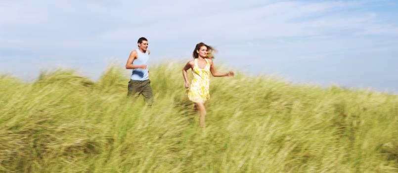 Couple running through meadow