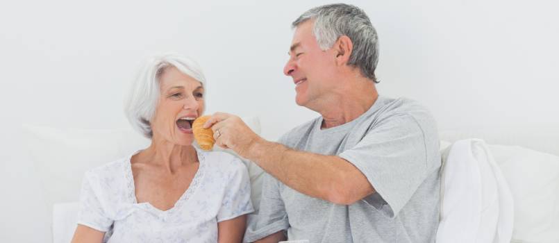 Man giving croissant to wife