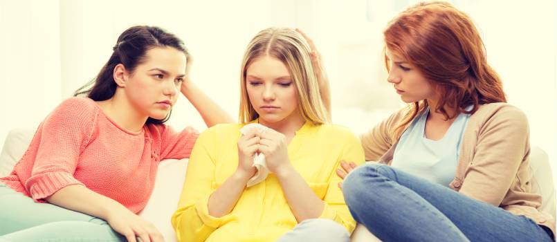 two teenage girls comforting another after breakup