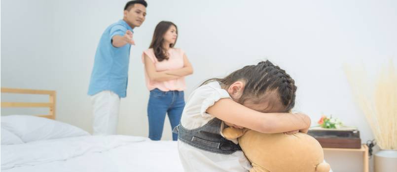 Little sad girl with parent quarrelling in bedroom