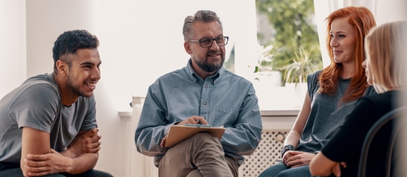 Smiling Spanish Man Talking To His Friends During Meeting For Teenagers With Therapist