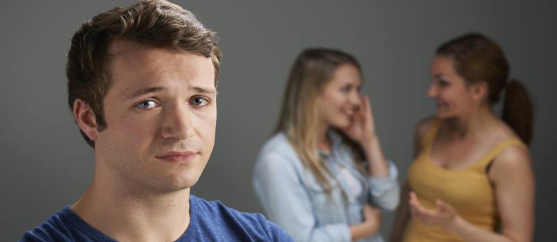 Worried man being talked about by women