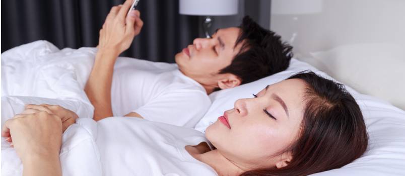 Women sleeping while husband using phone