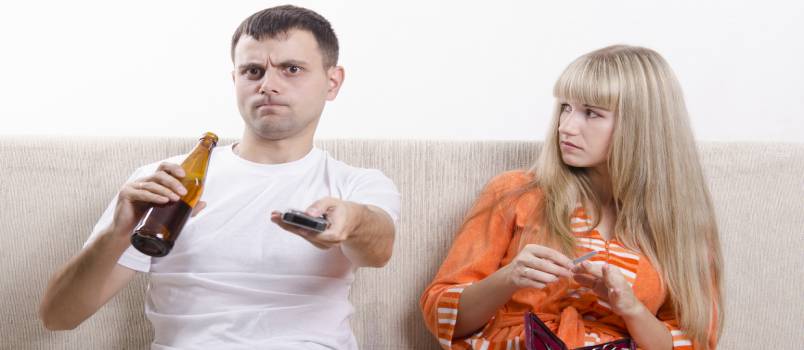 Man drinking beer while wife looking at him