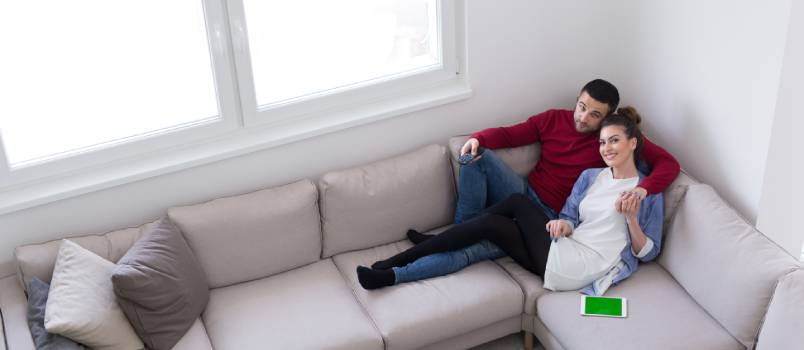Couple sitting on sofa watching television