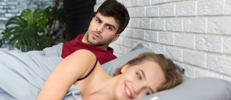 Jealous boyfriend shocked looking at man with his girlfriend using phone