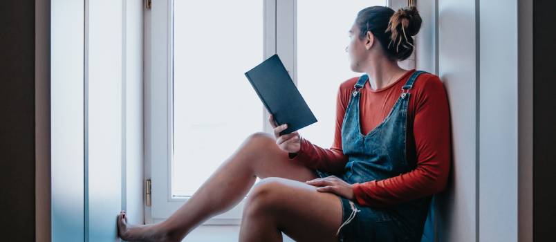 Woman sitting next to the window reading book