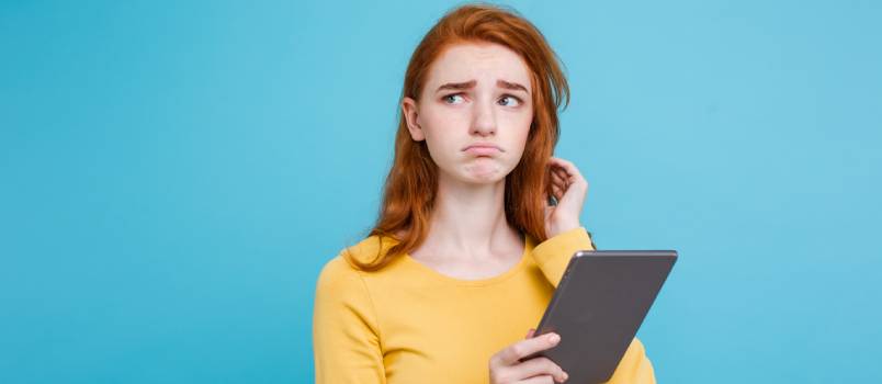 Woman using tablet while making sad faces