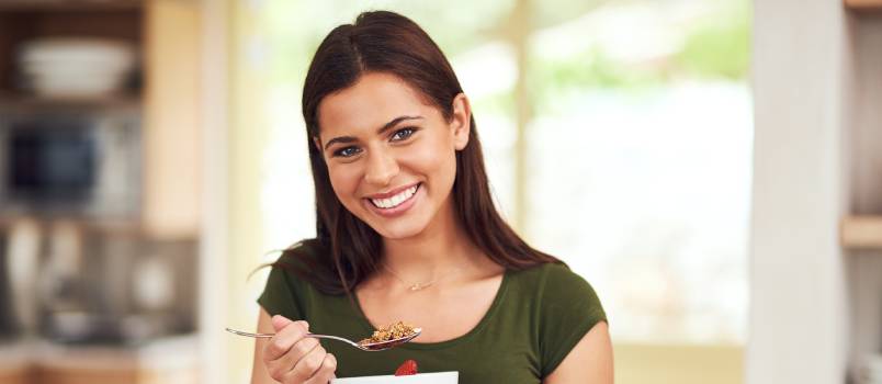 Woman having muesli in kitchen 