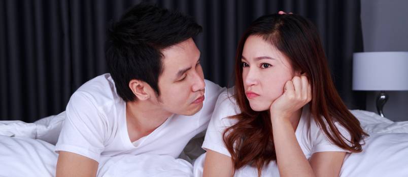 Woman laying on bed with concerned man