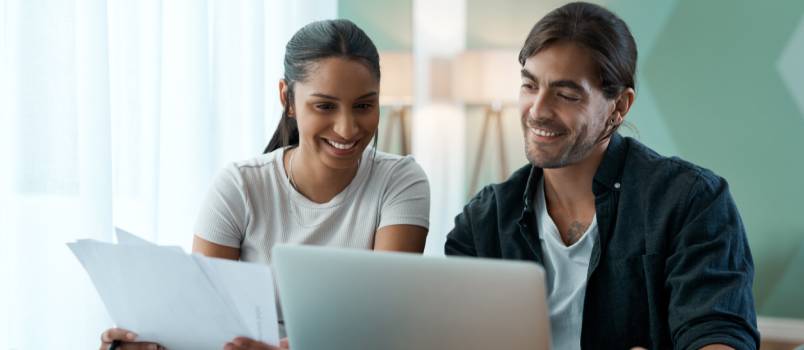 Couple doing paper work while using laptop