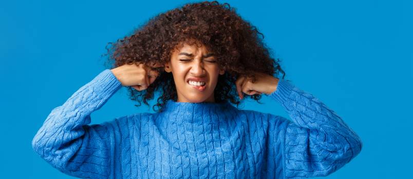 Woman shutting her ears with fingers due to loud music