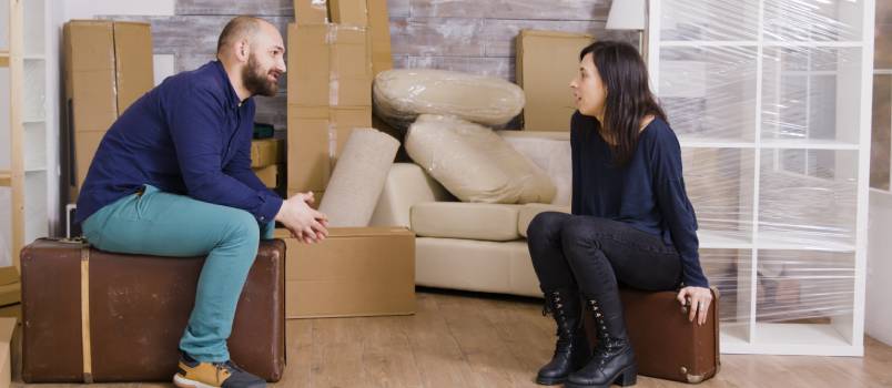 Couple taking sitting on suitcase
