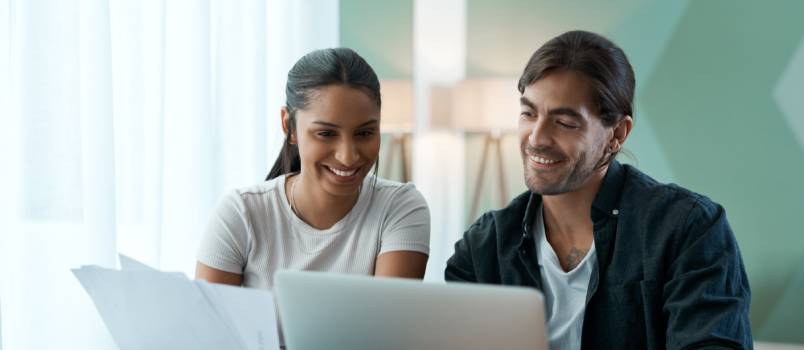 Young couple doing paperwork while using laptop