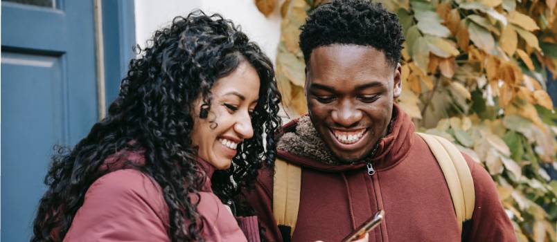 Cheerful couple smiling and sharing smartphone