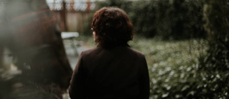 Man in black sitting near green grass