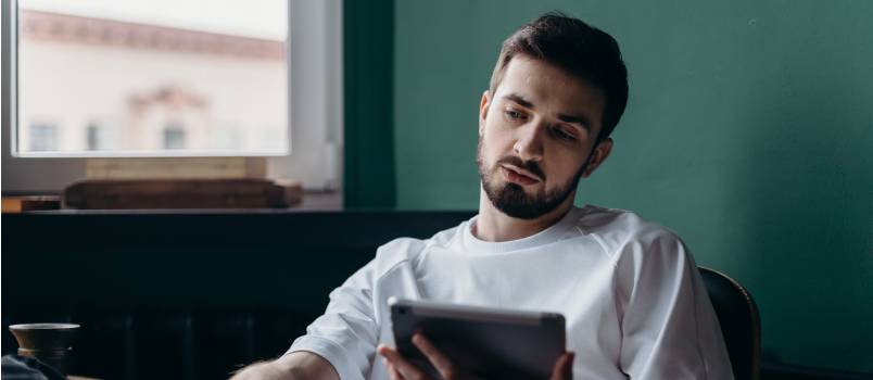 Man in white shirt holding ipad