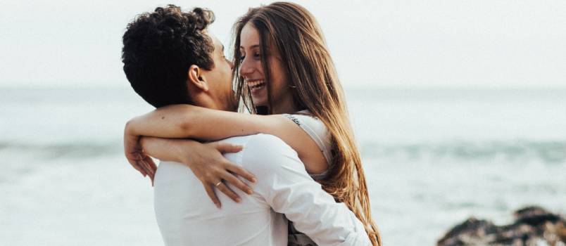 Man lifting woman near beach