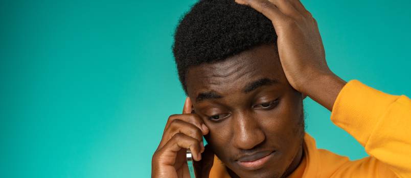 Man making sad face while talking on phone