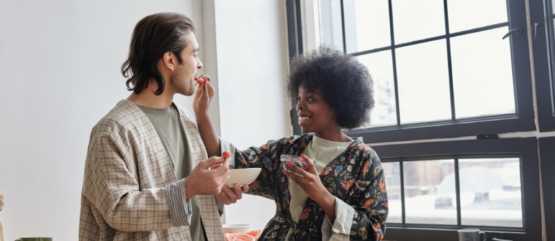 Woman feeding strawberry to man