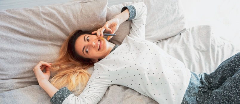 Woman sleeping on a bed and talking on the phone