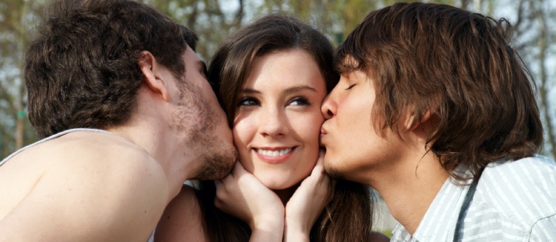 Happy girl kissed by two young boys