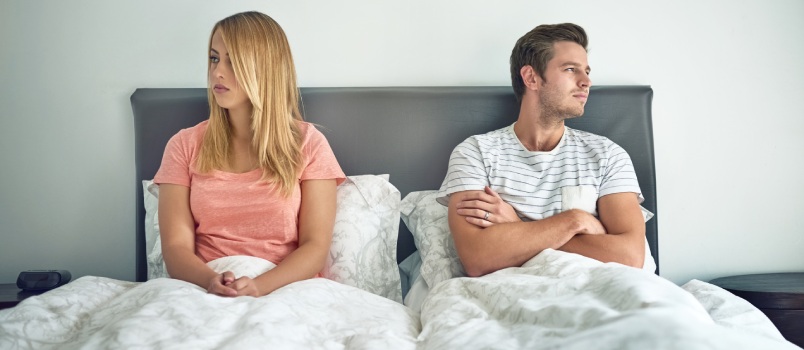 Couple sitting on bed not talking to each other