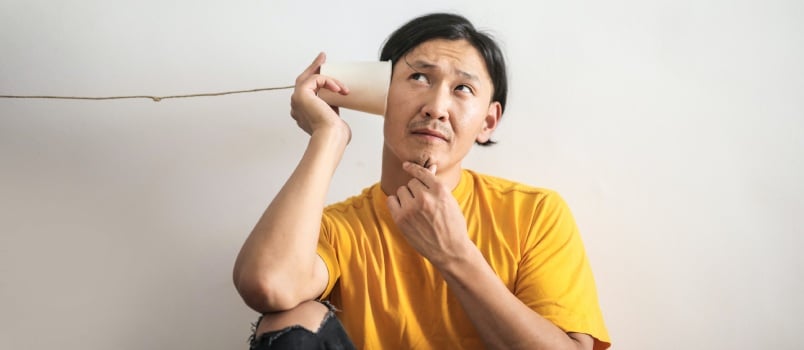 Man listening to answer through paper cup