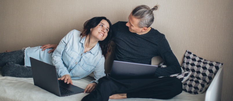 Couple smiling while working on laptop