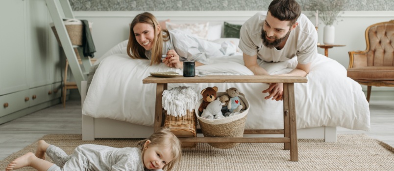 Couple laying on bed looking at their daughter