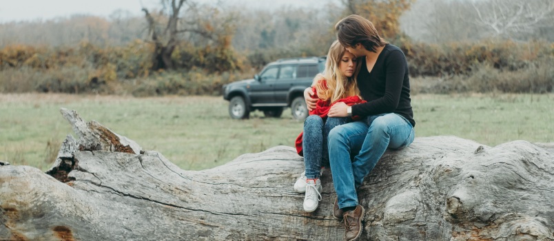 Mother and daughter sitting on tree log