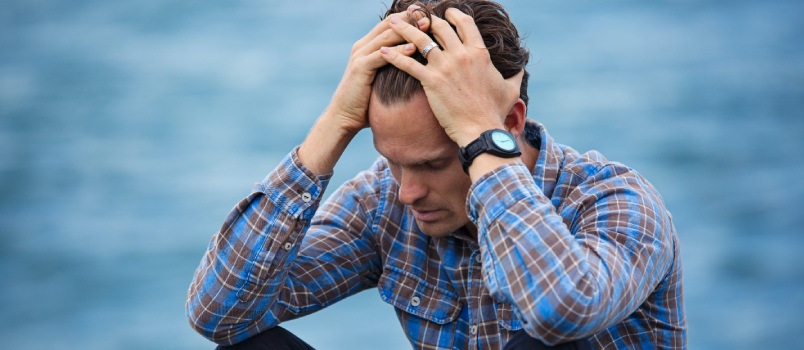 Depressed man sitting holding head