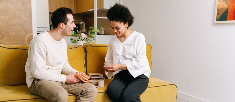 Man and woman sitting on yellow couch 