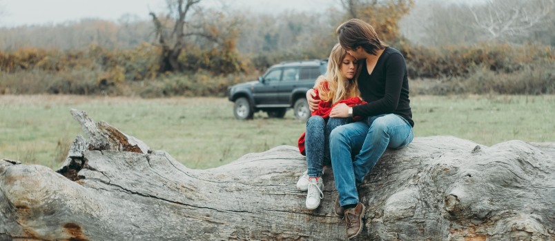 Mother and daughter sitting on tree wood