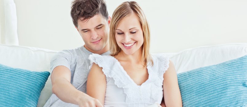 Couple reading book sitting on sofa