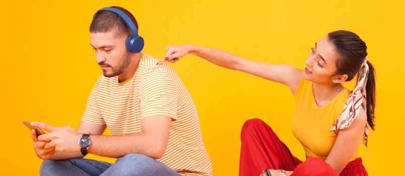 Boyfriend using his smartphone while girlfriend is annoying him