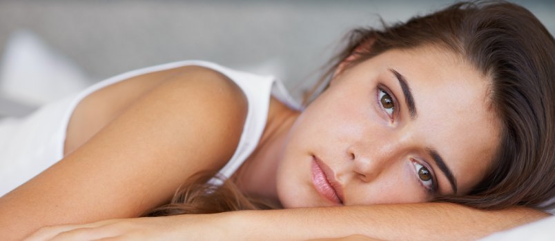 Young woman looking sad while laying