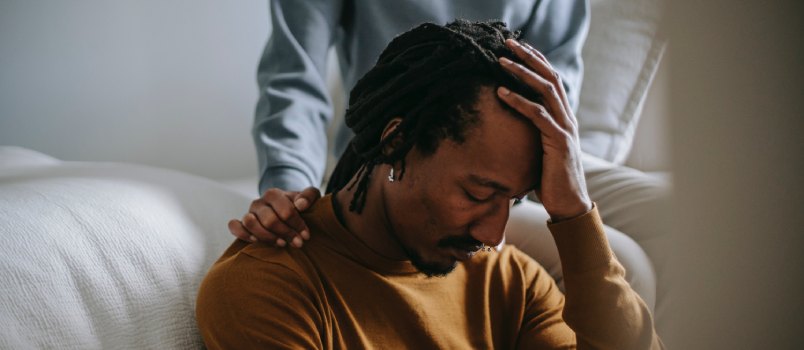 Black man touching his head while wife is confronting him