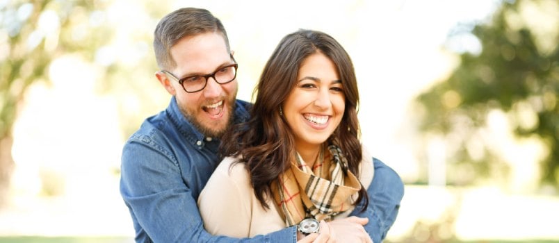 Happy young man hugging woman from back