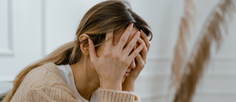 Woman sitting covering her face