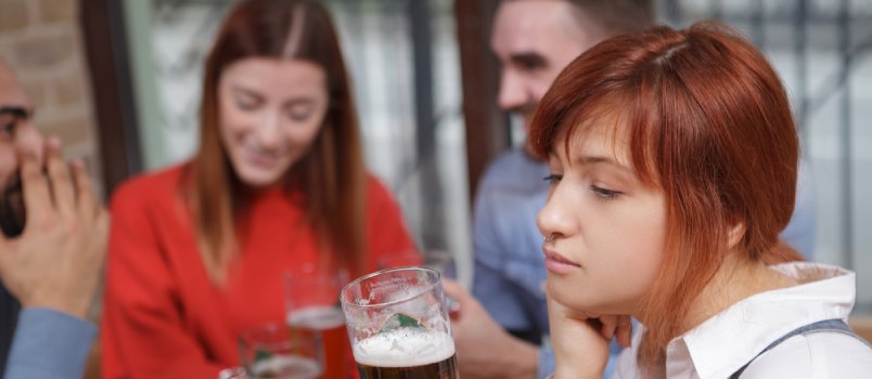 Sad woman drinking beer at pub
